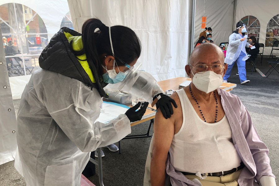 Victor Villegas, 78, right, receives a COVID-19 vaccine shot from a health care worker at a vaccination site in the Mission district of San Francisco, Monday, Feb. 8, 2021. (AP Photo/Haven Daley)