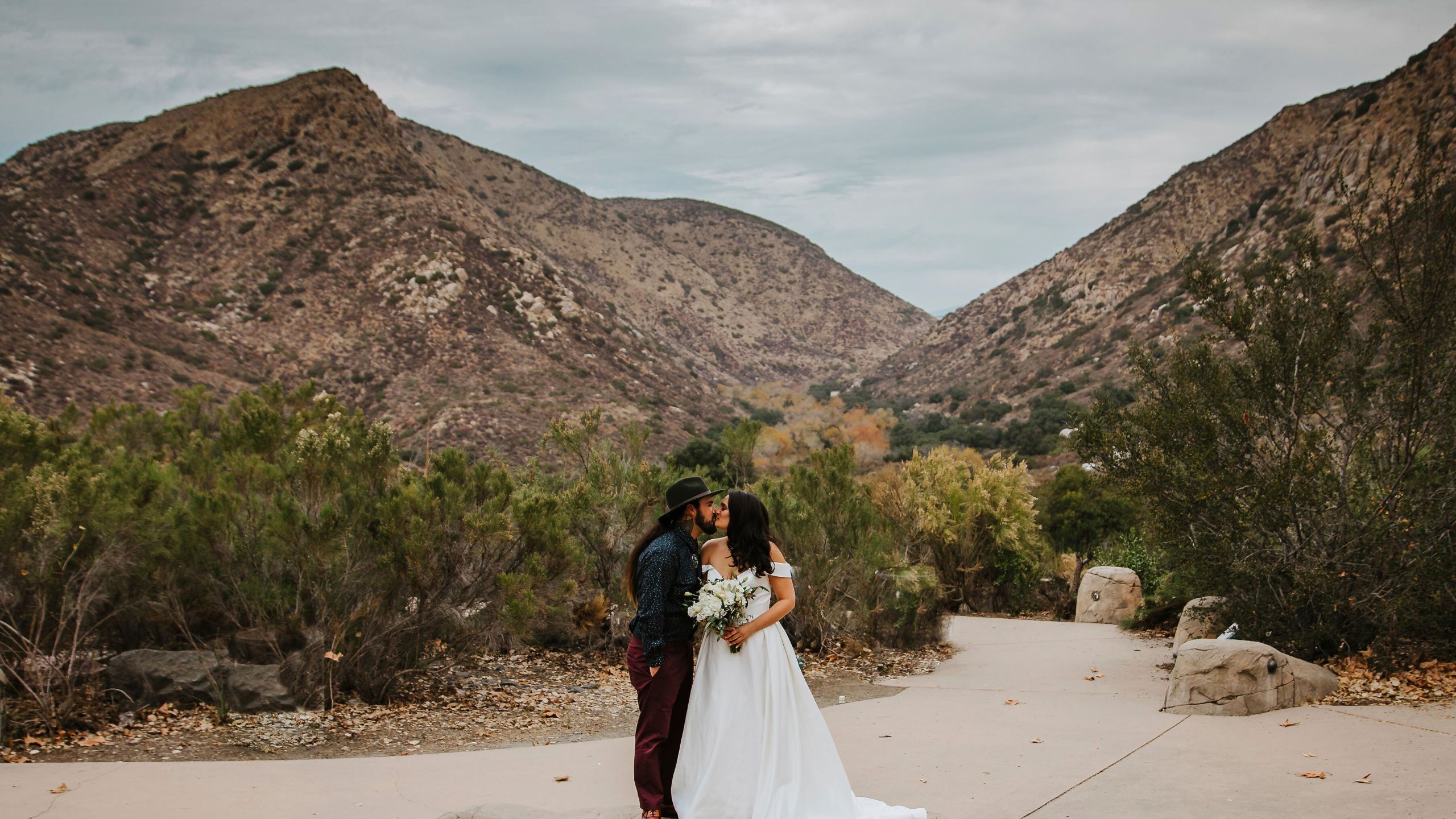 In this Sunday, Dec. 27, 2020 photo provided by Kristen Pritchard Photography, Kayleigh and Cody Cousins pose for wedding photos at Mission Trails Regional Park in San Diego, Calif. They initially planned an April 2020 wedding, postponed it after the pandemic took hold, rescheduled it for December, then had to shift gears again when a new lockdown was imposed. “That was devastating,” said Kayleigh. “We said, ‘Let’s just do it on Zoom.’” (Kristen Pritchard Photography via AP)