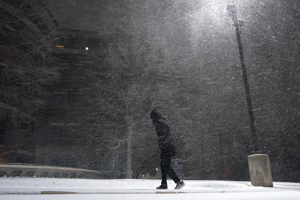 A woman walks through falling snow in San Antonio, Sunday, Feb. 14, 2021. (AP Photo/Eric Gay)