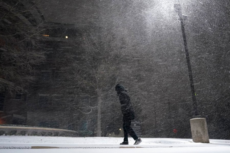 A woman walks through falling snow in San Antonio, Sunday, Feb. 14, 2021. (AP Photo/Eric Gay)