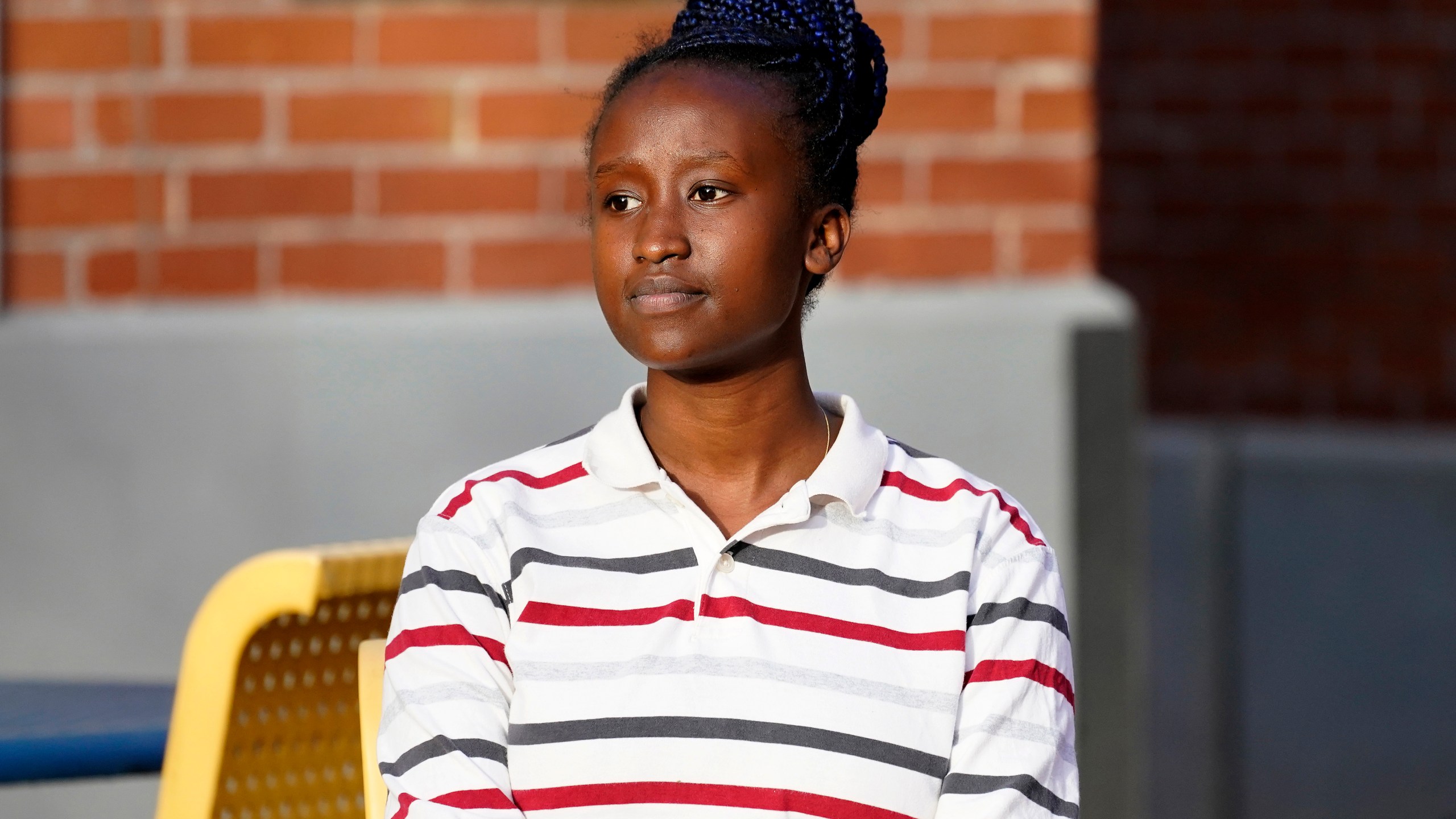 Peniella Irakoze sits on campus during a break from her part-time job at Phoenix College Thursday, Jan. 28, 2021 in Phoenix. Irakoze is working through a list of more than 1,000 fellow students who didn’t return to Phoenix College this semester, calling to check how they’re doing during the coronavirus pandemic. The National Student Clearinghouse says enrollment at U.S. community colleges dropped 10% from fall 2019 to fall 2020 amid the pandemic. (AP Photo/Matt York)