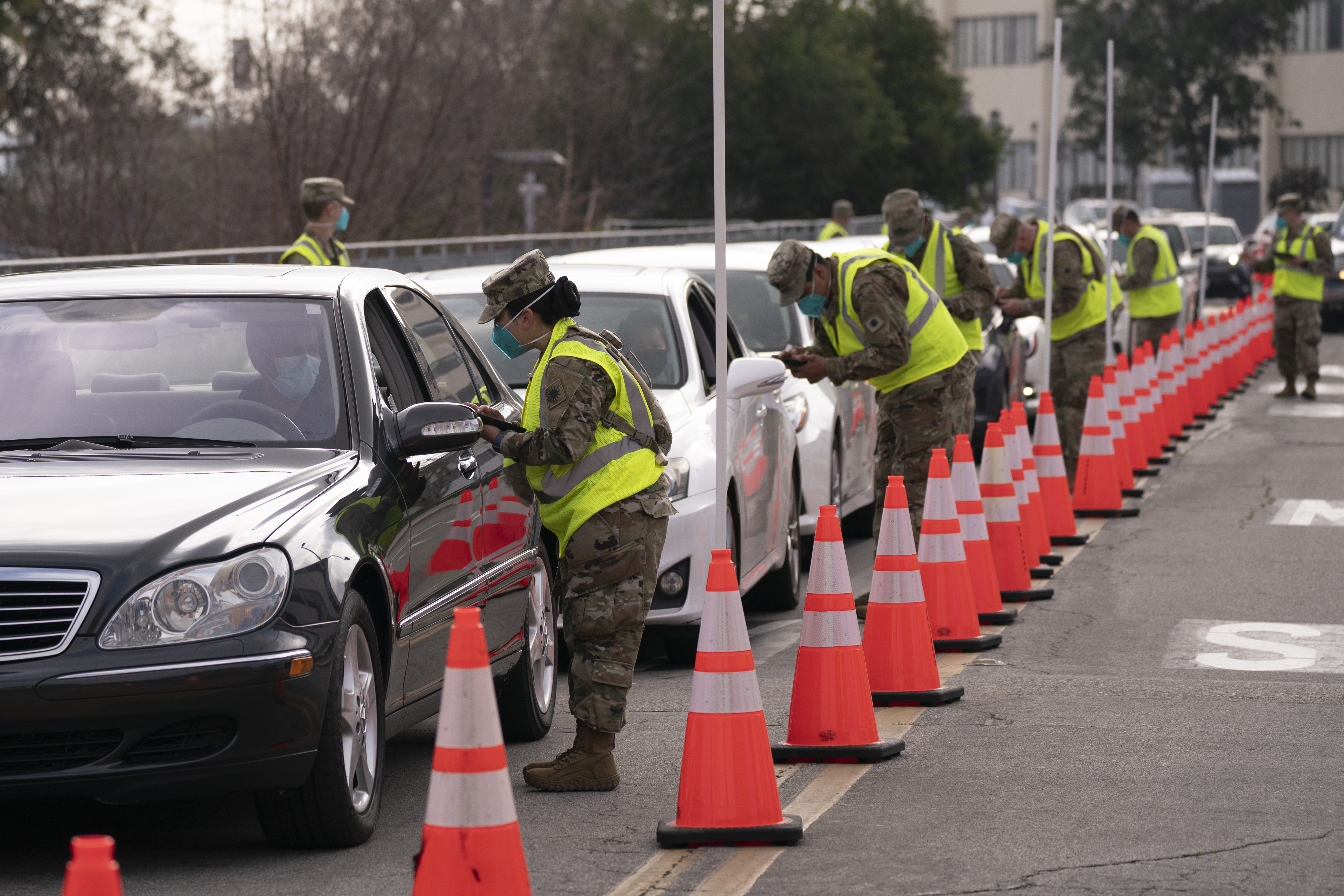 Members of the National Guard help motorists check in at a federally-run COVID-19 vaccination site set up on the campus of California State University of Los Angeles on Feb. 16, 2021. (AP Photo/Jae C. Hong)