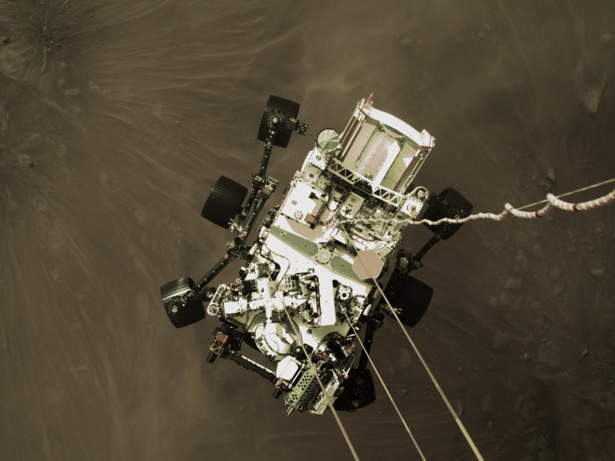 This Feb. 18, 2021 photo provided by NASA shows the Perseverance rover lowered towards the surface of Mars during its powered descent.