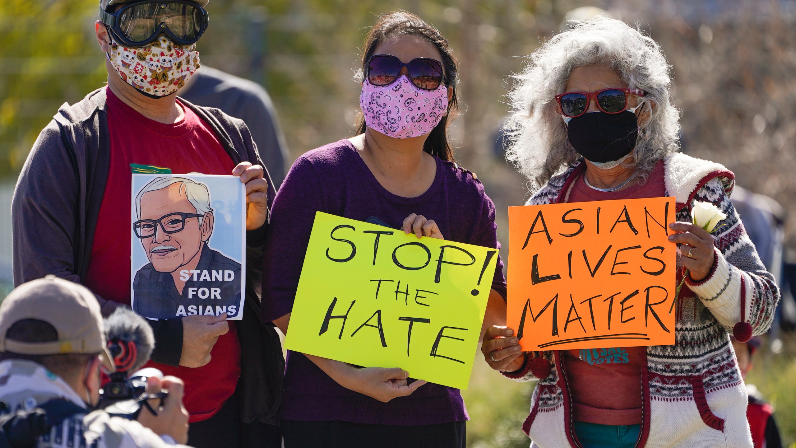 A man holds a portrait of late Vichar Ratanapakdee, left, a 84-year-old immigrant from Thailand, who was violently shoved to the ground in a deadly attack in San Francisco, during a community rally to raise awareness of anti-Asian violence and racist attitudes, in response to the string of violent racist attacks against Asians during the pandemic, held at Los Angeles Historic Park near the Chinatown district in Los Angeles on Feb. 20, 2021. (Damian Dovarganes / Associated Press)