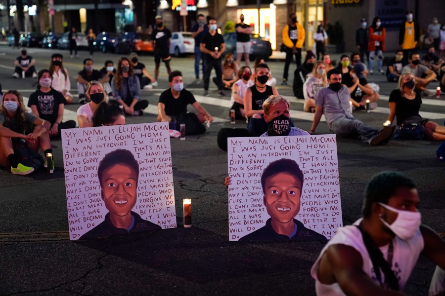 In this Aug. 24, 2020, file photo, two people hold posters showing images depicting Elijah McClain during a candlelight vigil for McClain outside the Laugh Factory in Los Angeles. (Jae C. Hong/Associated Press)