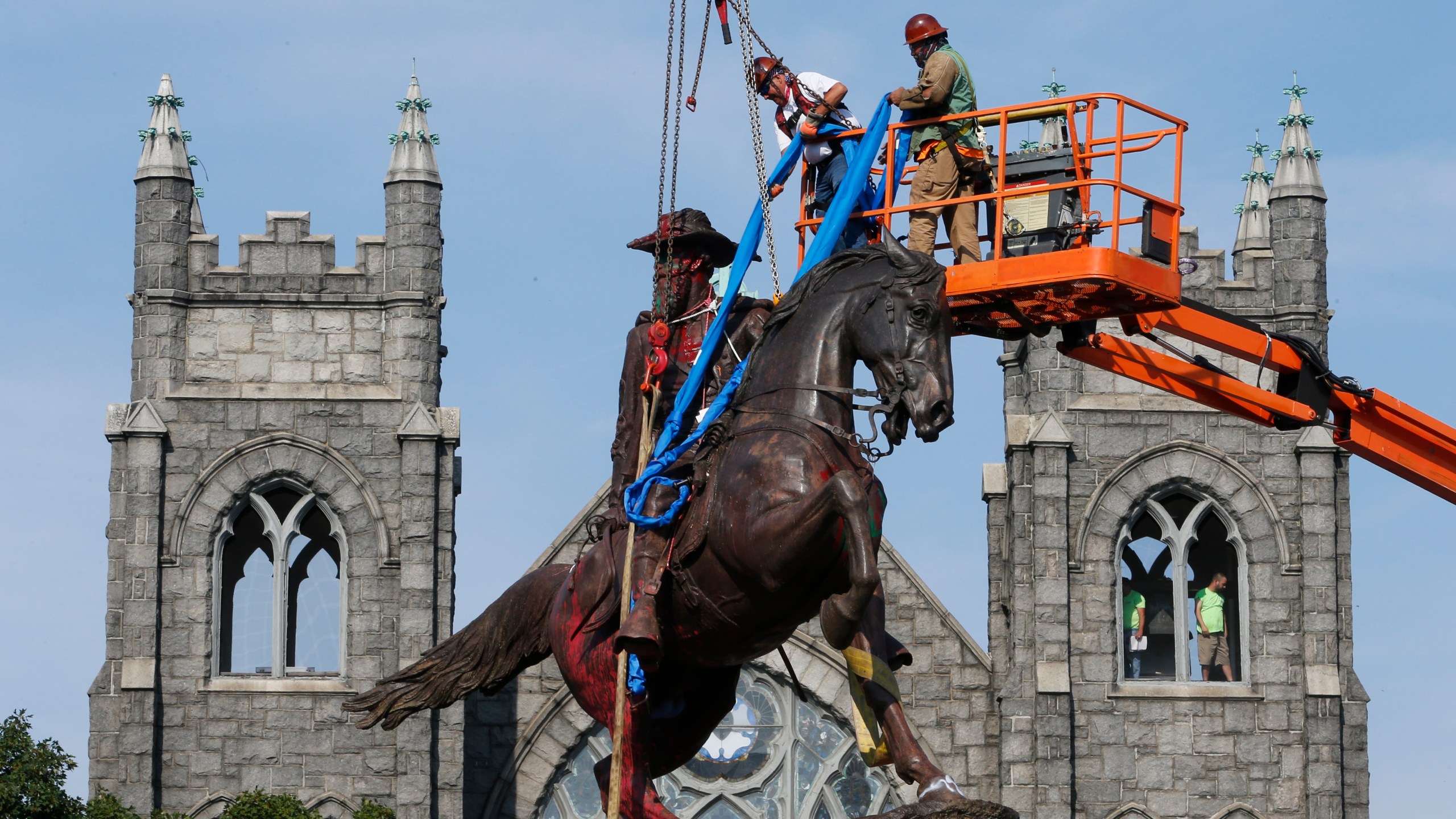 In this July 7, 2020, file photo, crews attach straps to the statue Confederate General J.E.B. Stuart on Monument Avenue in Richmond, Va. At least 160 Confederate symbols were taken down or moved from public spaces in 2020. That's according to a new count the Southern Poverty Law Center shared with The Associated Press. (AP Photo/Steve Helber, File)