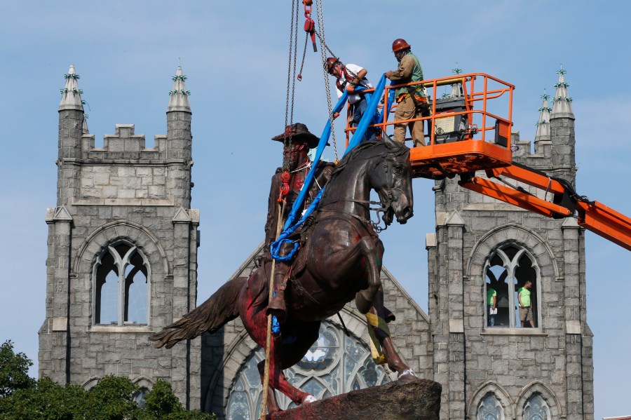 In this July 7, 2020, file photo, crews attach straps to the statue Confederate General J.E.B. Stuart on Monument Avenue in Richmond, Va. At least 160 Confederate symbols were taken down or moved from public spaces in 2020. That's according to a new count the Southern Poverty Law Center shared with The Associated Press. (AP Photo/Steve Helber, File)