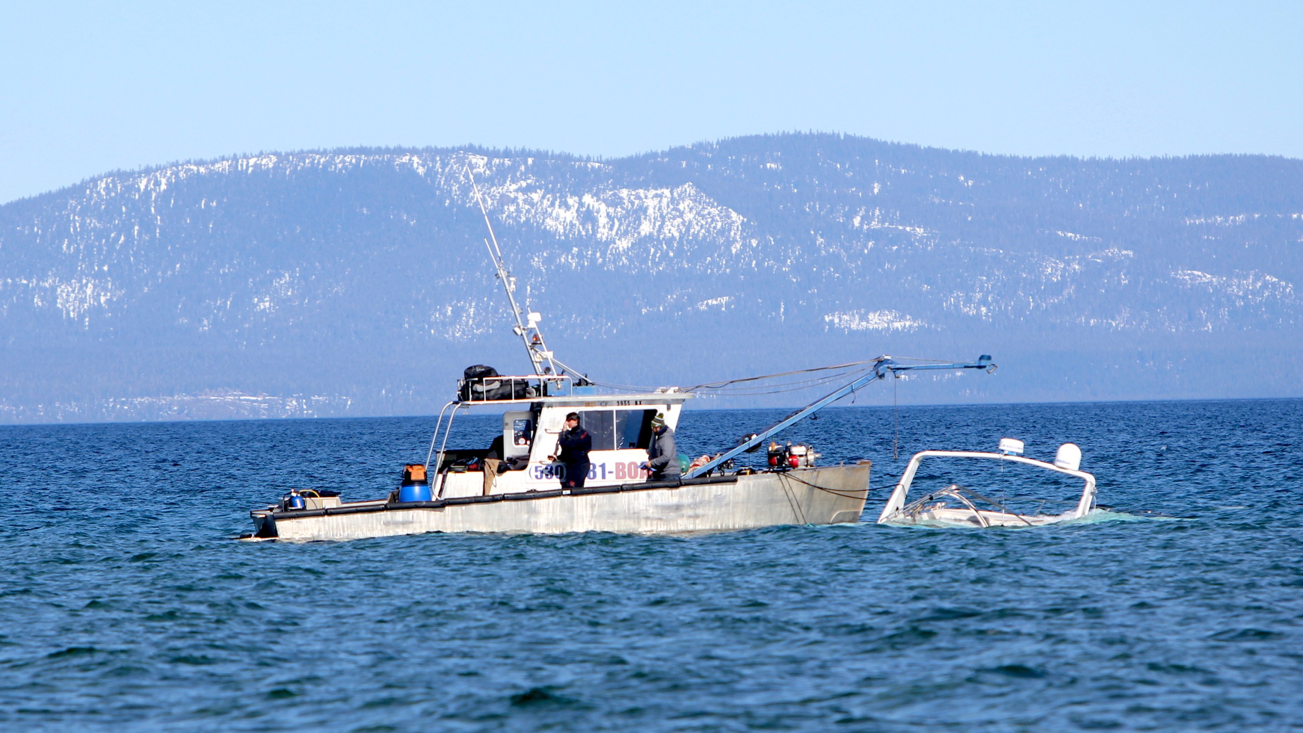 A crew for High Sierra Marine Inc. recovers a sunk boat , Tuesday, Feb. 23, 2021, of the shore of South Lake Tahoe. (Bill Rozak/The Tahoe Tribune via AP)