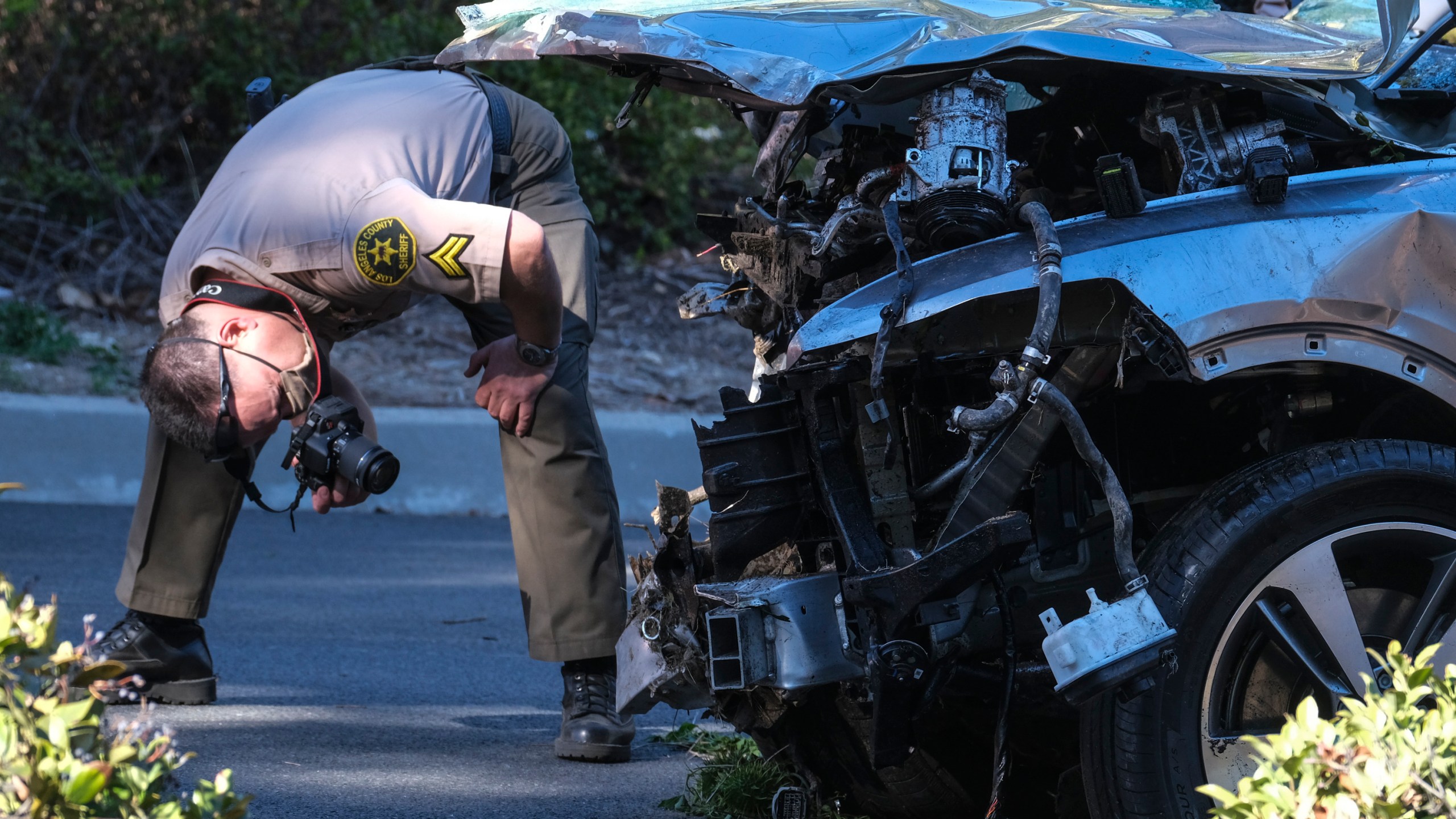 A law enforcement officer looks over a damaged vehicle following a rollover accident involving golfer Tiger Woods on Feb. 23, 2021, in the Rancho Palos Verdes suburb of Los Angeles. (Ringo H.W. Chiu / Associated Press)