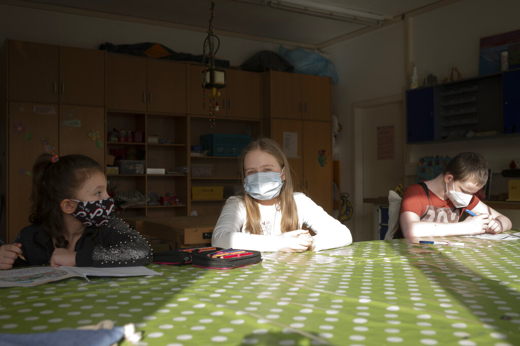 Nine-year-old girl Pollina Dinner, center, sits between other children in a schoolwork room at the Arche, or Ark, an organization that supports children, youth and families in the Hellersdorf neighbourhood, on the eastern outskirts of Berlin, Germany, Tuesday, Feb. 23, 2021. (AP Photo/Markus Schreiber)