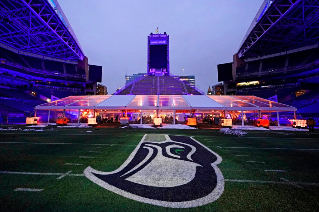 People eat dinner in an outdoor dining tent set up near the logo of the Seattle Seahawks NFL football team on the 50-yard line at Lumen Field, Thursday, Feb. 18, 2021, in Seattle. (AP Photo/Ted S. Warren)