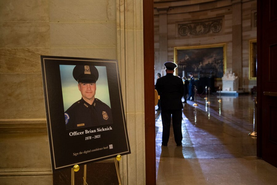 In this Feb. 2, 2021, file photo a placard is displayed with an image of the late U.S. Capitol Police officer Brian Sicknick on it as people wait for an urn with his cremated remains to be carried into the U.S. Capitol to lie in honor in the Capitol Rotunda in Washington. (Brendan Smialowski/Pool via AP, File)