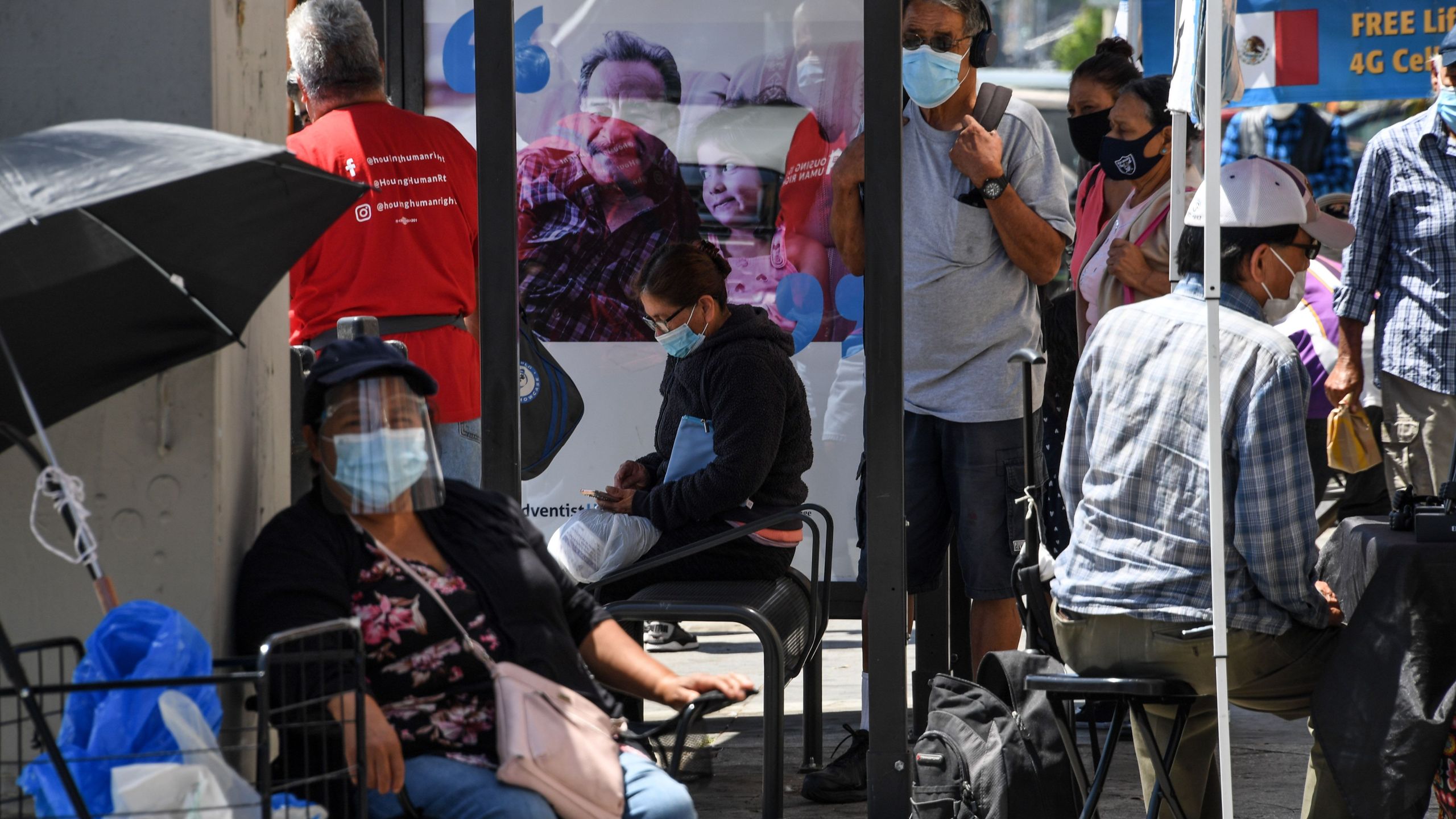 People wait for a bus in a neighborhood of East Los Angeles, Aug. 7, 2020 in Los Angeles, California during the coronavirus pandemic. (Robyn Beck/AFP via Getty Images)