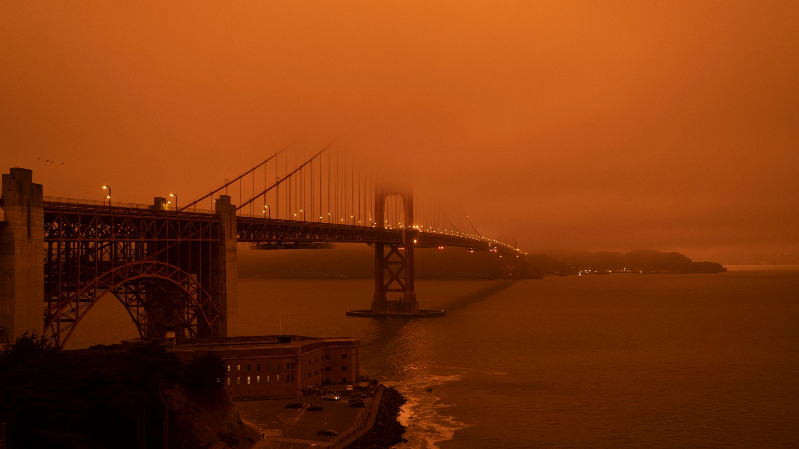 Cars drive along the Golden Gate Bridge under an orange smoke filled sky at midday in San Francisco, California on Sept. 9, 2020. (HAROLD POSTIC/AFP via Getty Images)