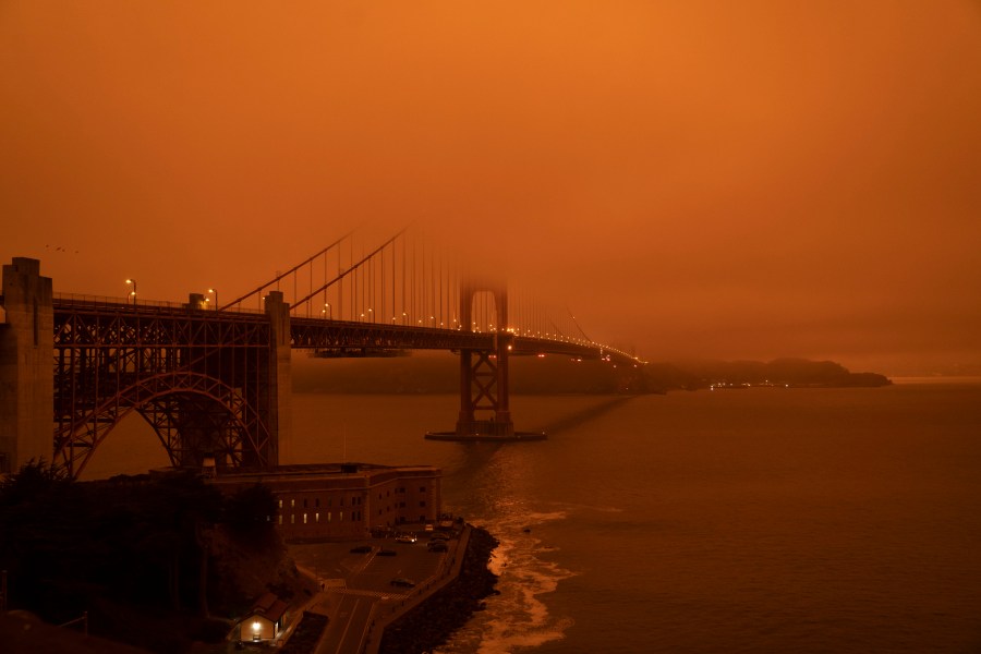 Cars drive along the Golden Gate Bridge under an orange smoke filled sky at midday in San Francisco, California on Sept. 9, 2020. (HAROLD POSTIC/AFP via Getty Images)