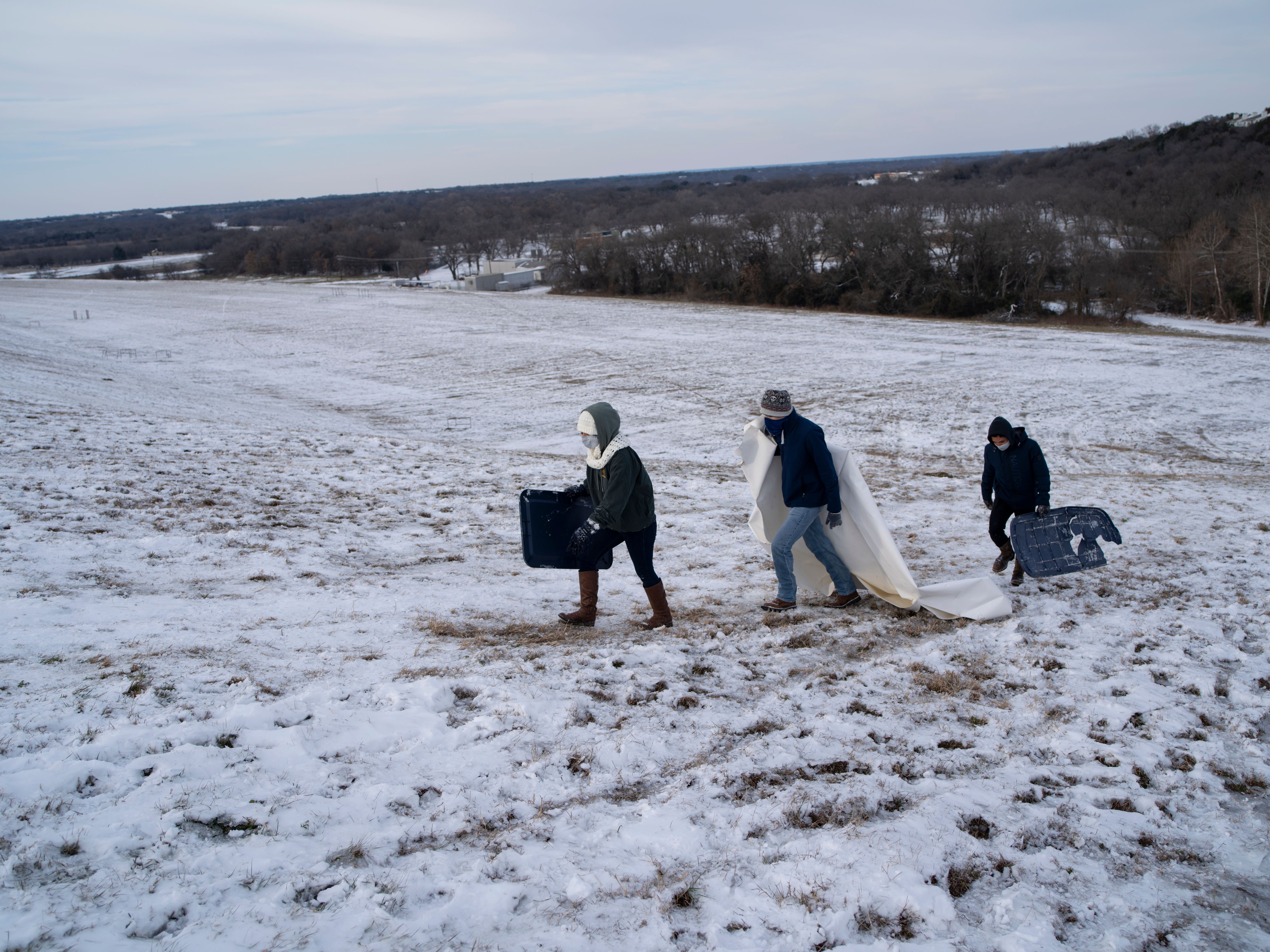 Connie Mendoza, Alberto Torres and Jazy Mendoza climb up a steep hill next to Lake Waco dam in Waco, Texas on Thursday, Feb. 18, 2021. (MATTHEW BUSCH/AFP via Getty Images)