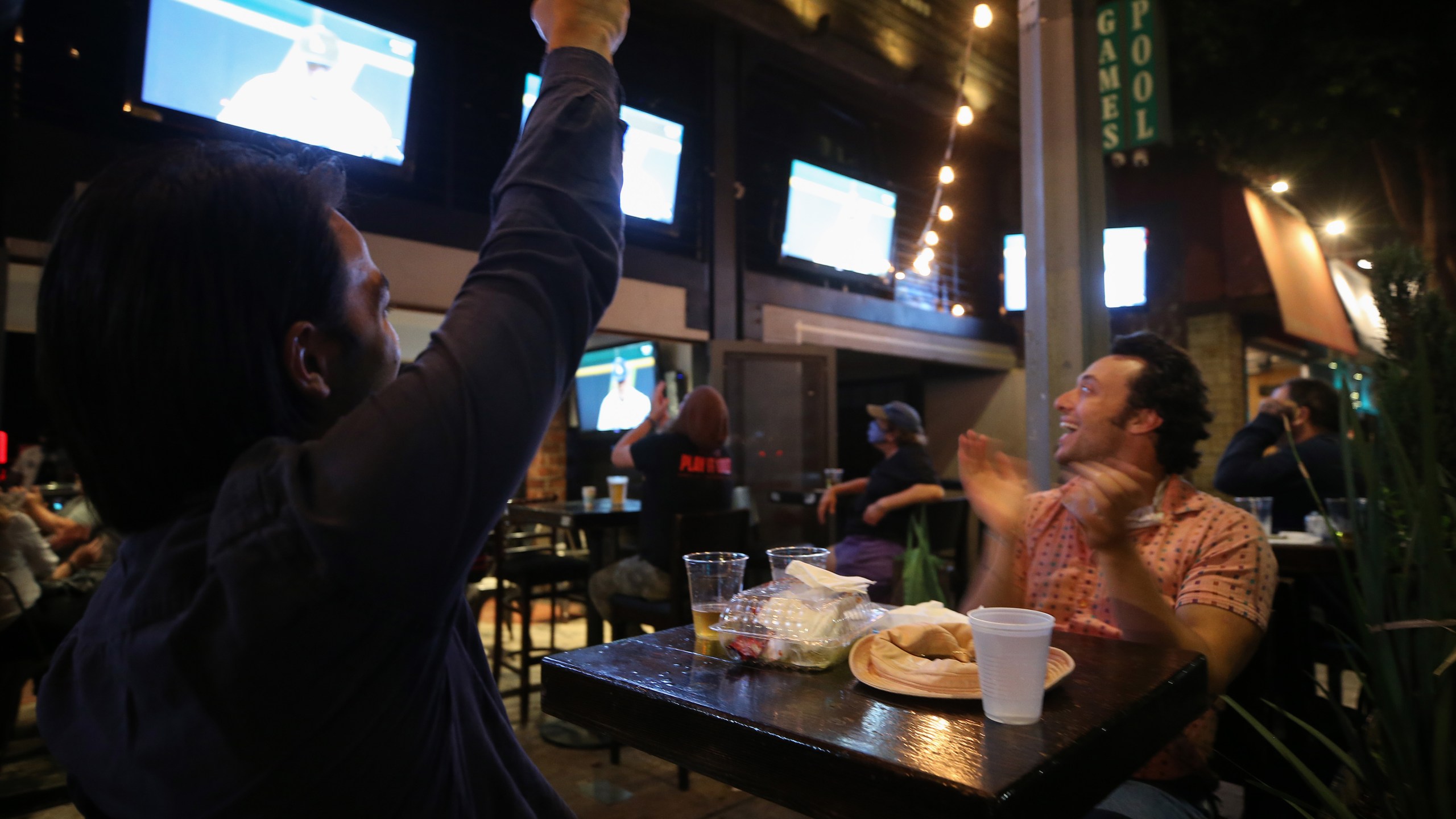 Los Angeles Dodgers fans cheer while watching a television broadcast of Game 1 of the 2020 World Series between the Dodgers and the Tampa Bay Rays at an outdoor bar and restaurant on Oct. 20, 2020 in Los Angeles, California.(Mario Tama/Getty Images)