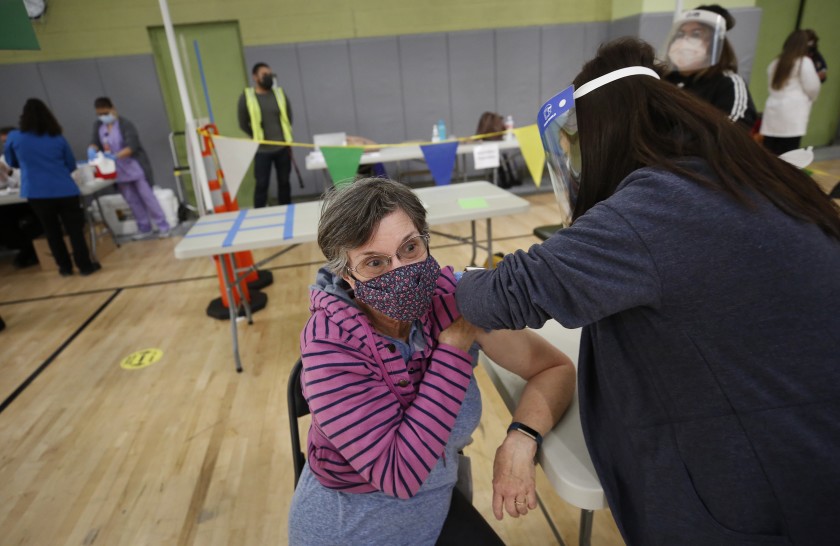 Los Angeles substitute teacher Jane Golliver, 67 receives her COVID-19 vaccination last week from Mary Ann Topico, right, in a pilot clinic at Roybal Learning Center, west of downtown, that provided 100 doses.(Al Seib / Los Angeles Times)