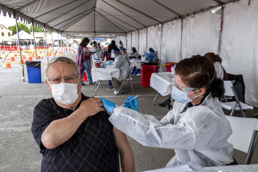 Robert Nelson, 81, of Riverside, left, gets a COVID-19 vaccine shot from nurse Susan Eyman in the parking lot of the Riverside Convention Center on Feb. 1, 2021. (Gina Ferazzi / Los Angeles Times)