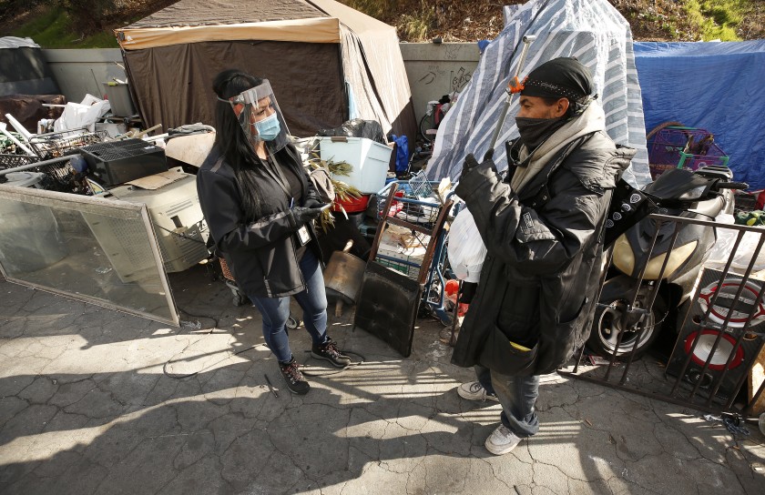 Marisol Barroso, left, a Los Angeles Homeless Services Authority, outreach worker, surveys a client named Ace last week in Inglewood. With L.A. County’s annual count of homeless people canceled this year because of the pandemic, some are suggesting it’s time to move on from the massive volunteer effort to a more data-savvy method.(Al Seib / Los Angeles Times)