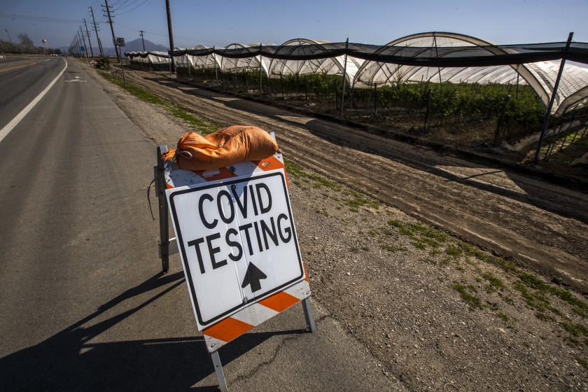 A sign points to COVID-19 testing available to farmworkers close to where they work near a hoop greenhouse in Oxnard in this undated photo. (Brian van der Brug / Los Angeles Times)