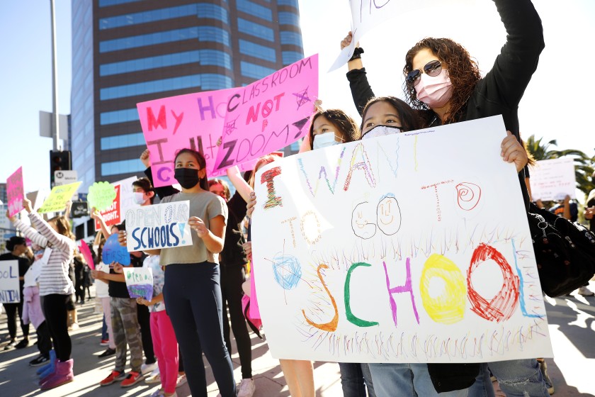 Mona Garcia, right, with her daughters Olivia, 8, front, and Maya, 11, of North Hills, participate in a demonstration Monday outside the West L.A. Federal Building to pressure the L.A. Unified School District to bring students back for in-person instruction and other services. (Christina House/Los Angeles Times)