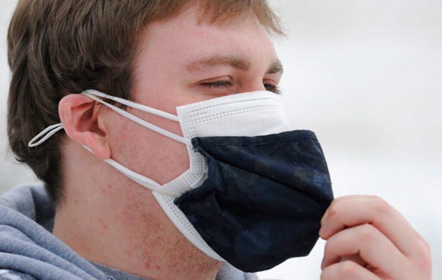 Wearing double masks, Mark Holton, a Lock Haven student home on break, walks his puppy Bella during a winter storm in Monroe Township, Wyoming County, Pa., Tuesday, Jan. 26, 2021. (Mark Moran /The Citizens' Voice via AP)