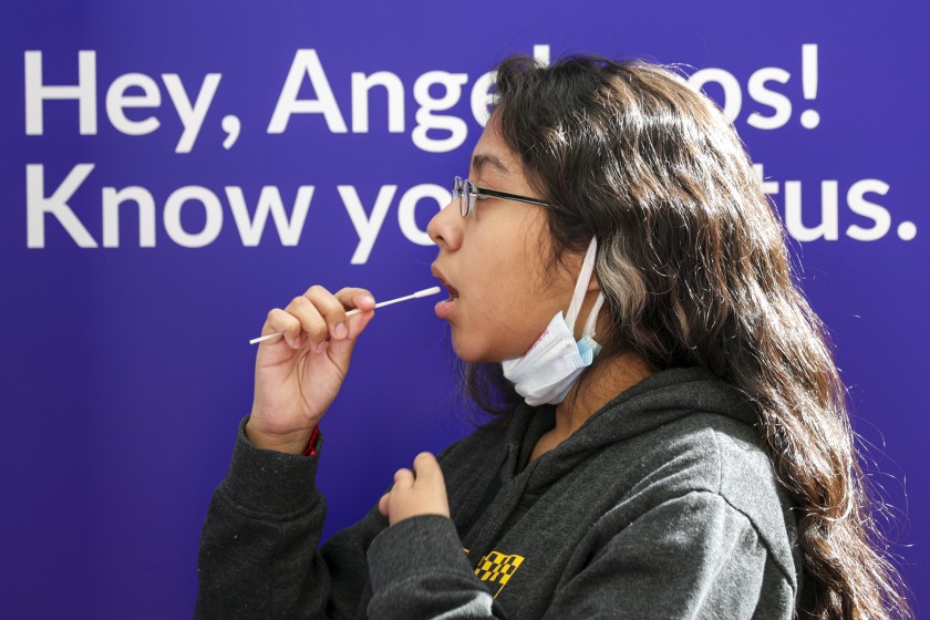 Laura Robles takes a self-administered oral swab COVID-19 test at Union Station in Los Angeles in this undated photo. (Irfan Khan /Los Angeles Times)