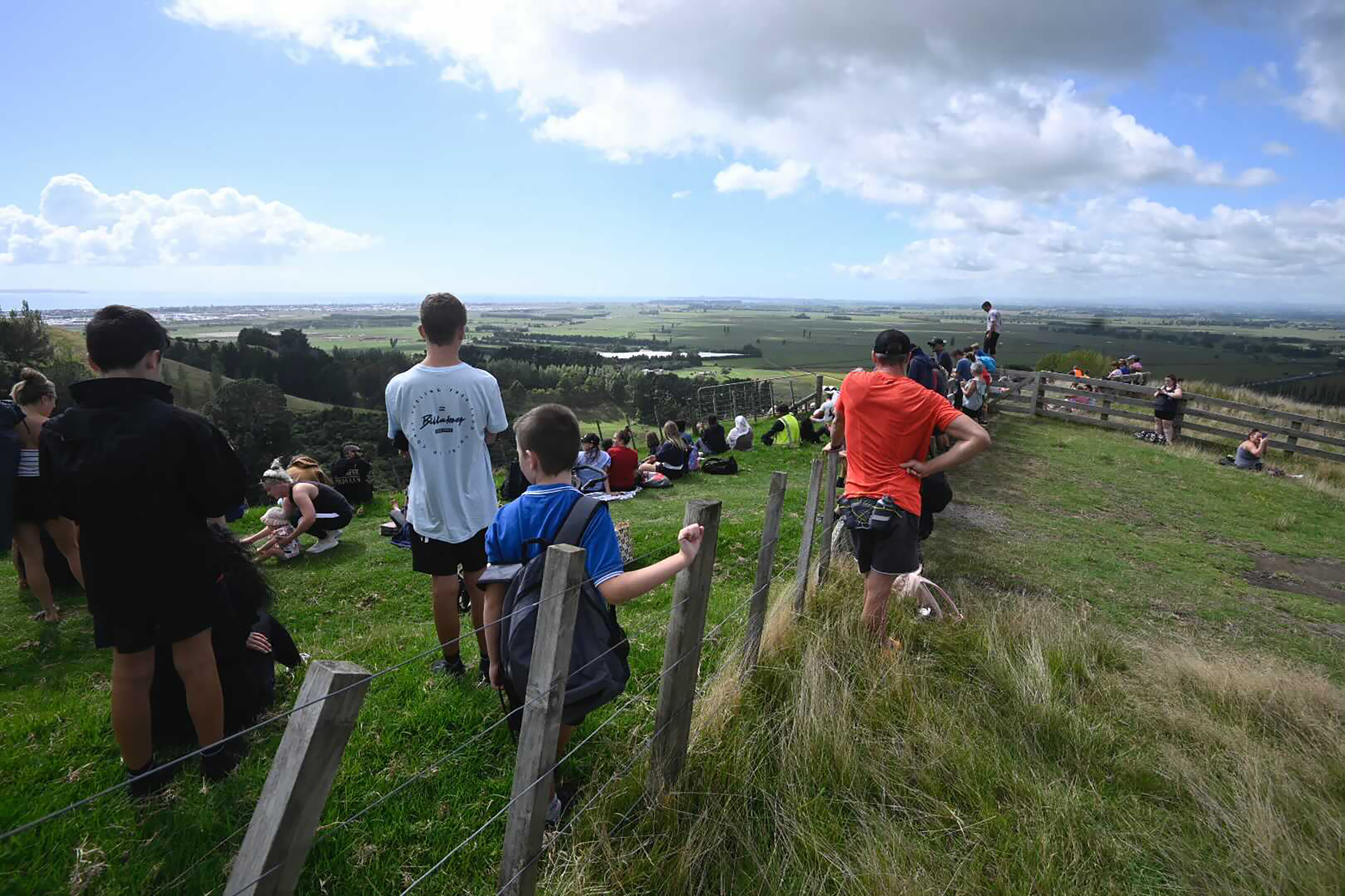 People watch for signs of a tsunami from a hill above Papamoa Beach, New Zealand, as a tsunami warning is issued on March 5, 2021. (George Novak / New Zealand Herald via Associated Press)