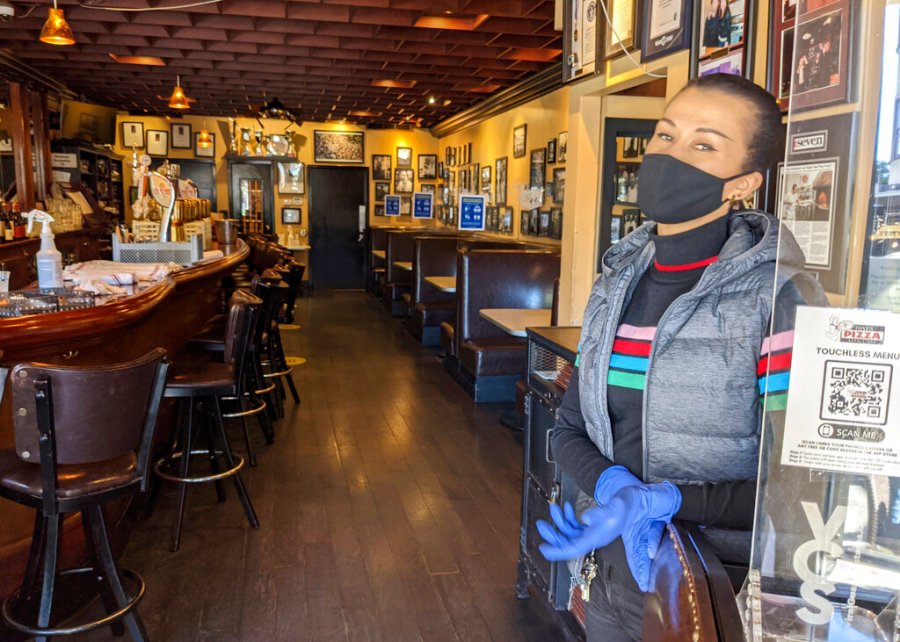 Ro Hart, an assistant general manager and hostess at Tony’s Pizza Napoletana in San Francisco stands in front of a totally empty indoors seating area during the lunch hour on Thursday, March 4, 2021. (AP Photo/Mike Liedtke)