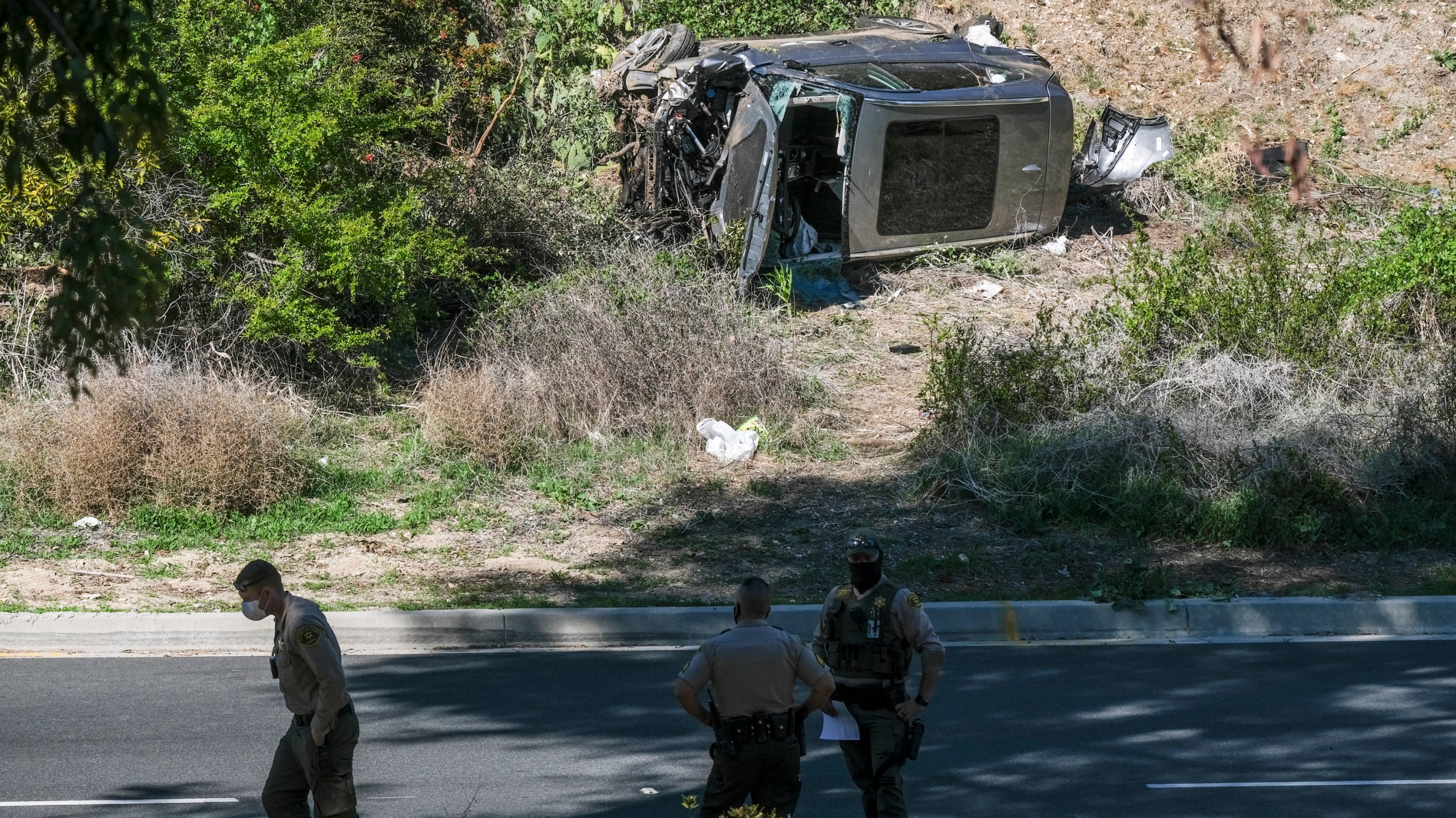 In this Feb. 23, 2021, file photo a vehicle rests on its side after a rollover accident involving golfer Tiger Woods along a road in the Rancho Palos Verdes suburb of Los Angeles. (AP Photo/Ringo H.W. Chiu, File)