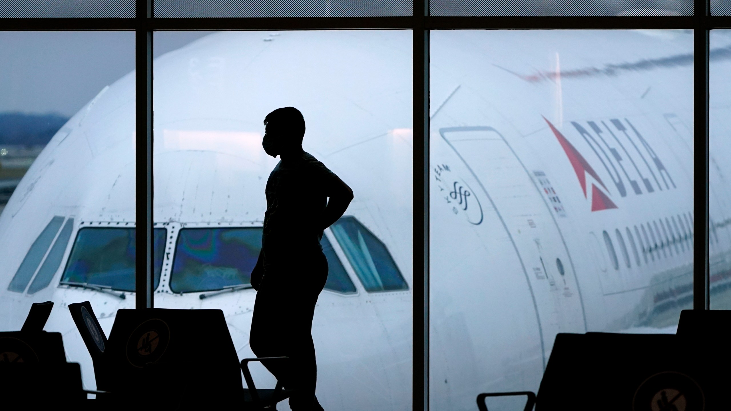 In this Feb. 18, 2021 file photo, a passenger wears a face mask to help prevent against the spread of the coronavirus as he waits for a Delta Airlines flight at Hartsfield-Jackson International Airport in Atlanta. (AP Photo/Charlie Riedel, File)