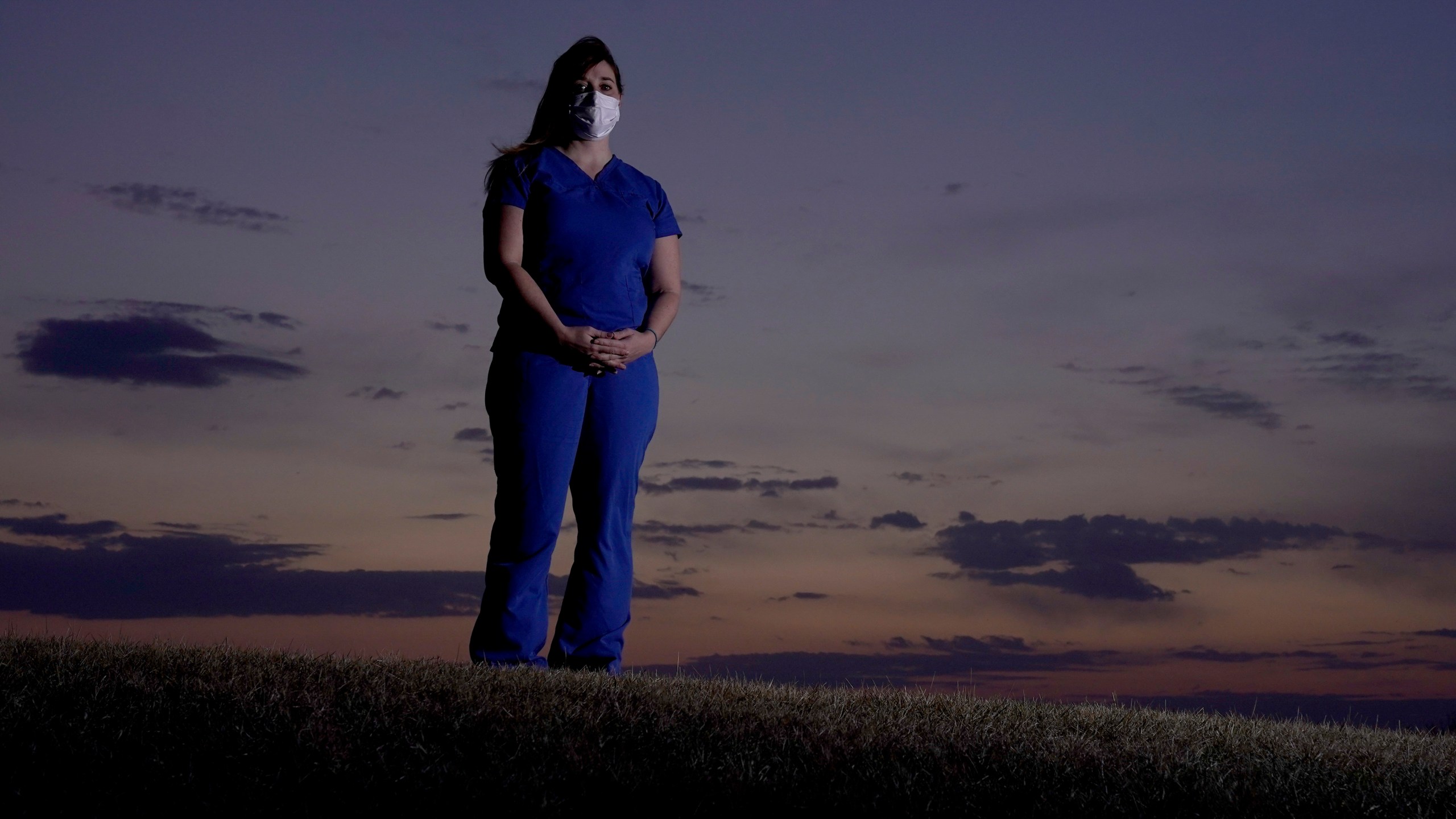 Emergency room nurse L'Erin Ogle stands at dawn before starting her 12-hour shift at a nearby hospital Tuesday, March 9, 2021, in Overland Park, Kan. (AP Photo/Charlie Riedel)