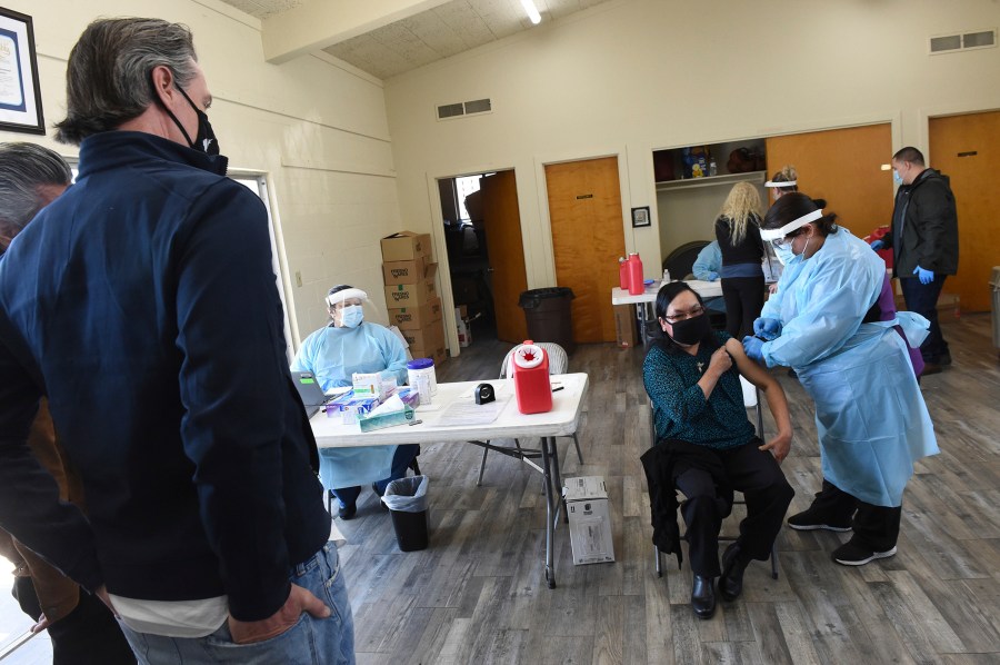 California Gov. Gavin Newsom watches as a farmworker receives the Pfizer COVID-19 vaccine at a vaccination clinic for farmworkers in Fresno on Feb. 26, 2021. (John Walker / The Fresno Bee via Associated Press)