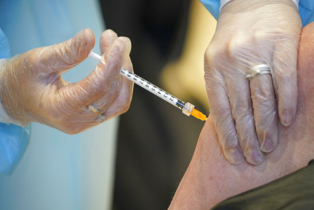 In this Wednesday, March 10, 2021 file photo, a health worker administers a dose of the AstraZeneca vaccine against COVID-19 to a patient inside the convention center known as "La Nuvola", The Cloud, in Rome. (AP Photo/Andrew Medichini, file)