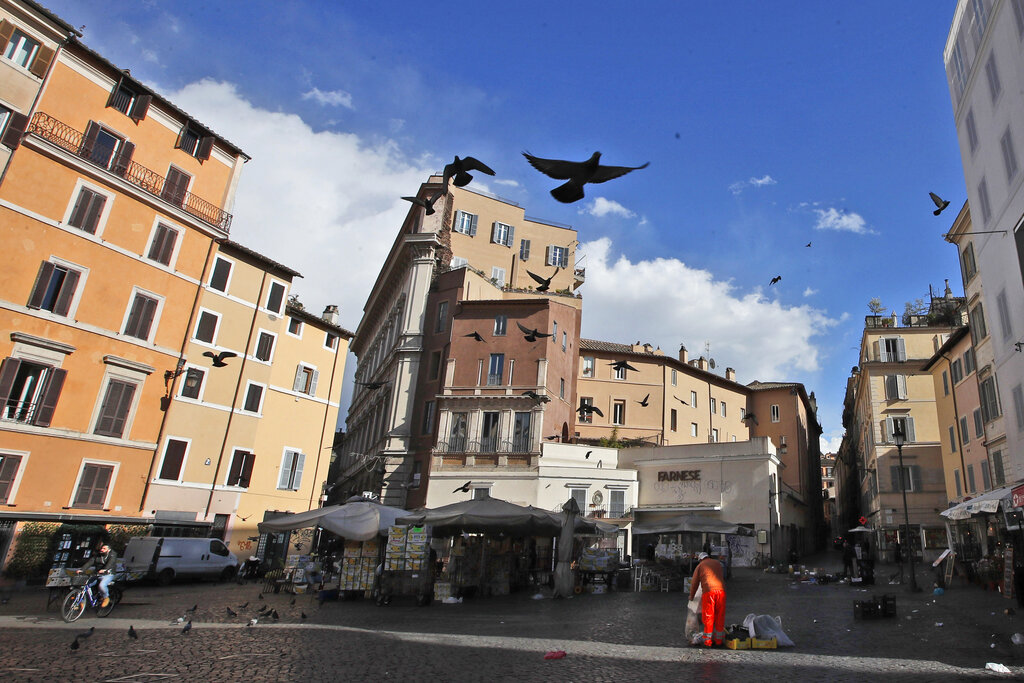 Pigeons fly over Rome's Campo dei Fiori Square, Monday, March 15, 2021. Half of Italy's regions have gone into the strictest form of lockdown in a bid to curb the latest spike in coronavirus infections that have brought COVID-19 hospital admissions beyond manageable thresholds. (AP Photo/Alessandra Tarantino)