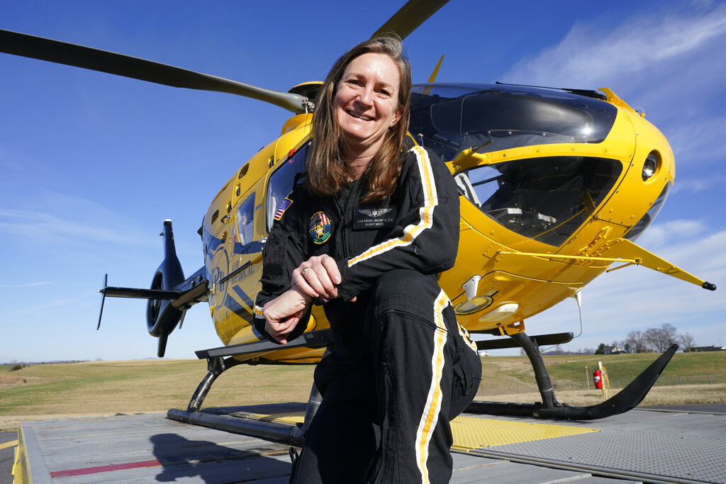 Air ambulance flight paramedic, Rita Krenz, poses in front of her company's helicopter in Weyers Cave, Va., Monday, March 15, 2021. Krenz started a fund-raising campaign that brought in more than $18,000 for the charity that has helped RIP Medical Debt forgive the debt of more than 900 people so far. (AP Photo/Steve Helber)