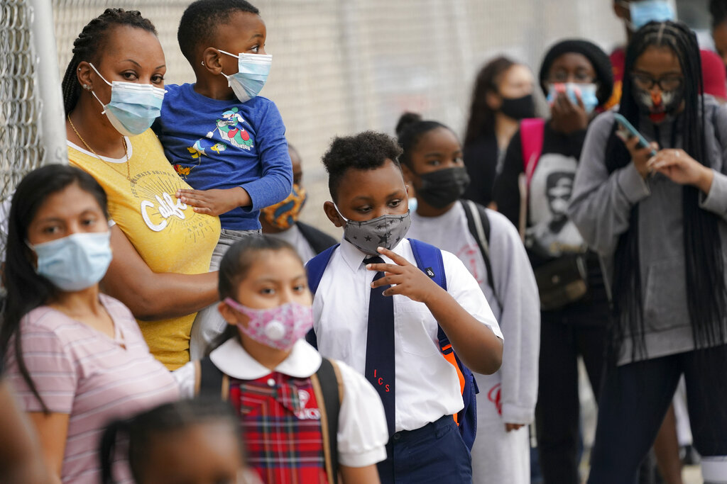 In this Sept. 9, 2020, file photo, students wear protective masks as they arrive for classes at the Immaculate Conception School while observing COVID-19 prevention protocols in The Bronx borough of New York. Schools and camps across the county are making plans to help kids catch up academically this summer after a year or more of remote learning for many of them. (AP Photo/John Minchillo, File)