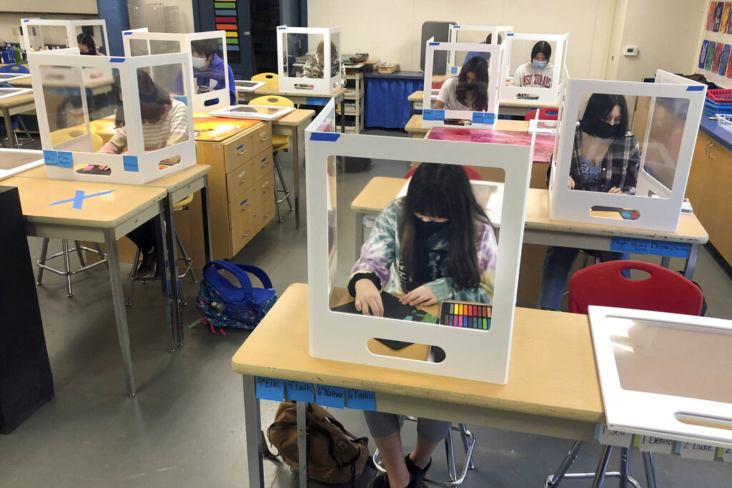 In this March 2, 2021, file photo, socially distanced, and with protective partitions, students work on an art project during class at the Sinaloa Middle School in Novato, California. (AP Photo/Haven Daley, File)