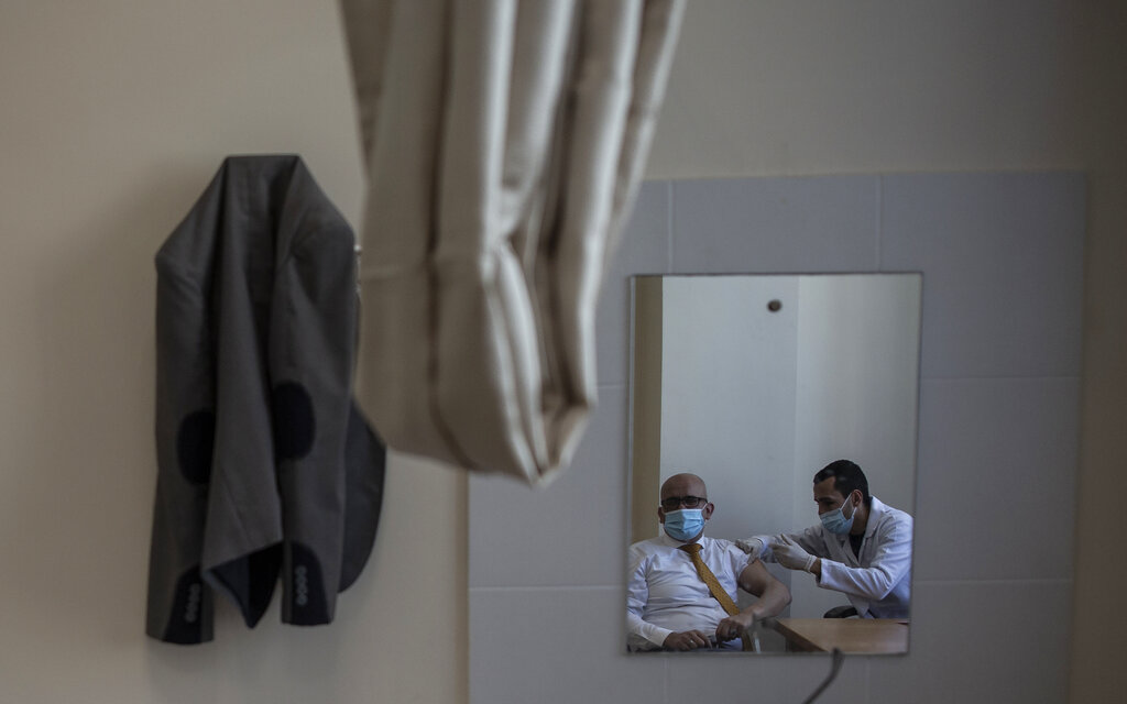 A Palestinian man receives a shot of the Russian-made Sputnik V coronavirus vaccine, at an UNRWA clinic in Gaza City, Wednesday, March 17, 2021. (AP Photo/Khalil Hamra)