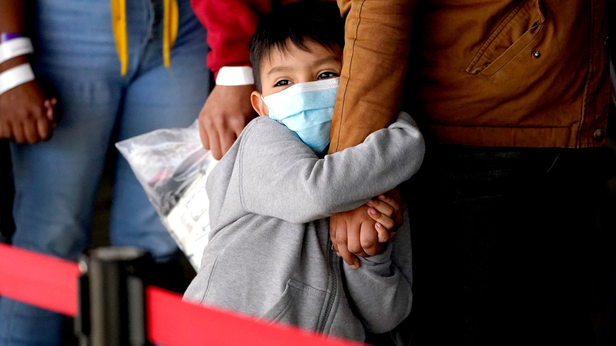 A migrant child holds onto a woman's arm as they wait to be processed by a humanitarian group after being released from U.S. Customs and Border Protection custody at a bus station, Wednesday, March 17, 2021, in Brownsville, Texas. (AP Photo/Julio Cortez)