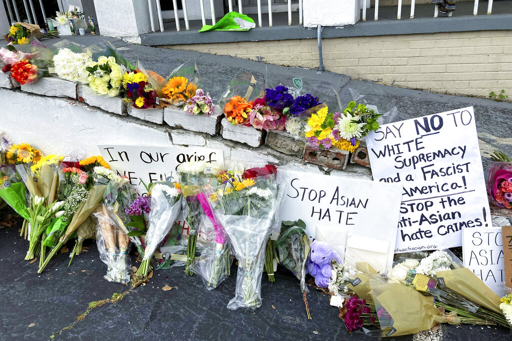 Flowers, candles and signs are displayed at a makeshift memorial on Friday, March 19, 2021, in Atlanta. (AP Photo/Candice Choi)