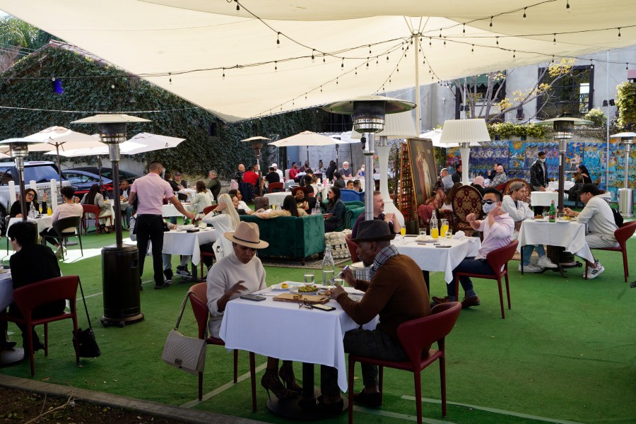 In this Feb. 14, 2021, file photo, people dine under a tent outside a restaurant in West Hollywood, Calif. The California Legislature has delayed a bill that would give a tax break for businesses because of a provision in the latest federal coronavirus relief bill that bans states form using federal stimulus dollars to pay for tax cuts. Gov. Gavin Newsom's administration is worried the U.S. Treasury Department might view the bill as a tax cut and require the state to pay back some of the stimulus money it is owed. (AP Photo/Damian Dovarganes, File)