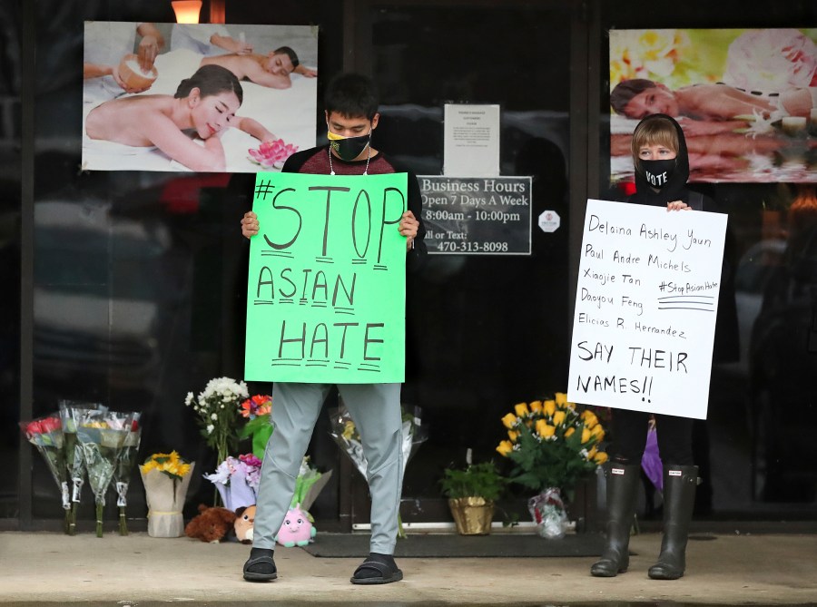 In this March 17, 2021, file photo, after dropping off flowers Jesus Estrella, left, and Shelby stand in support of the Asian and Hispanic community outside Young's Asian Massage in Acworth, Ga. (Curtis Compton /Atlanta Journal-Constitution via AP, File)