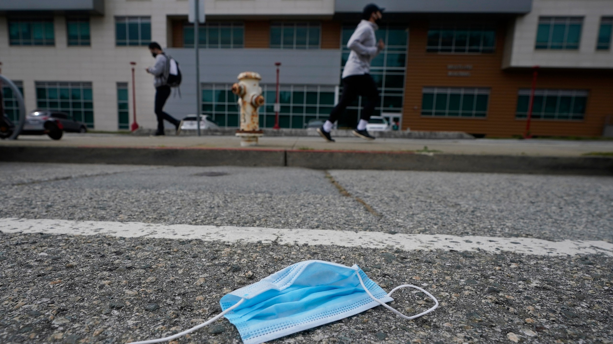 A discarded face mask lies in the street in San Francisco on March 17, 2021. (AP Photo/Jeff Chiu)