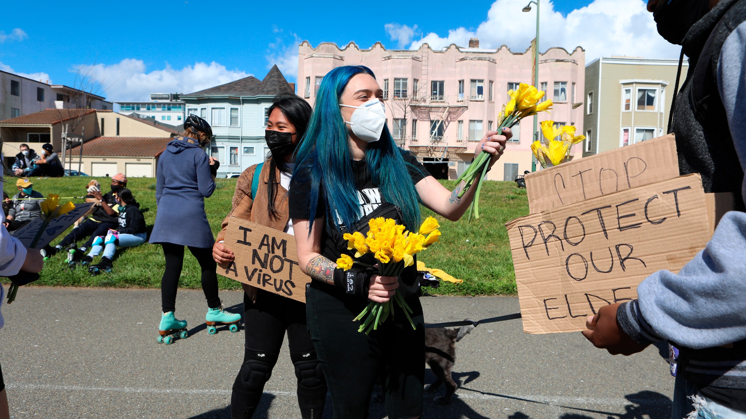 Organizer Ashley Silva distributes flowers to folks attending a rally organized in solidarity against racist violence against Asian Americans at Madison Park on March 20, 2021, in Oakland, Calif. (Yalonda M. James/San Francisco Chronicle via AP)