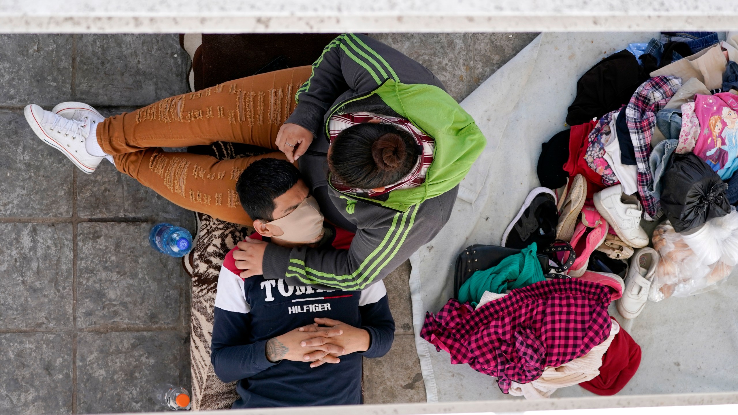 Migrants who were caught trying to cross into the U.S. and were deported rest under a ramp that leads to the McAllen-Hidalgo International Bridge in Reynosa, Mexico, on March 18, 2021. (Julio Cortez / Associated Press)