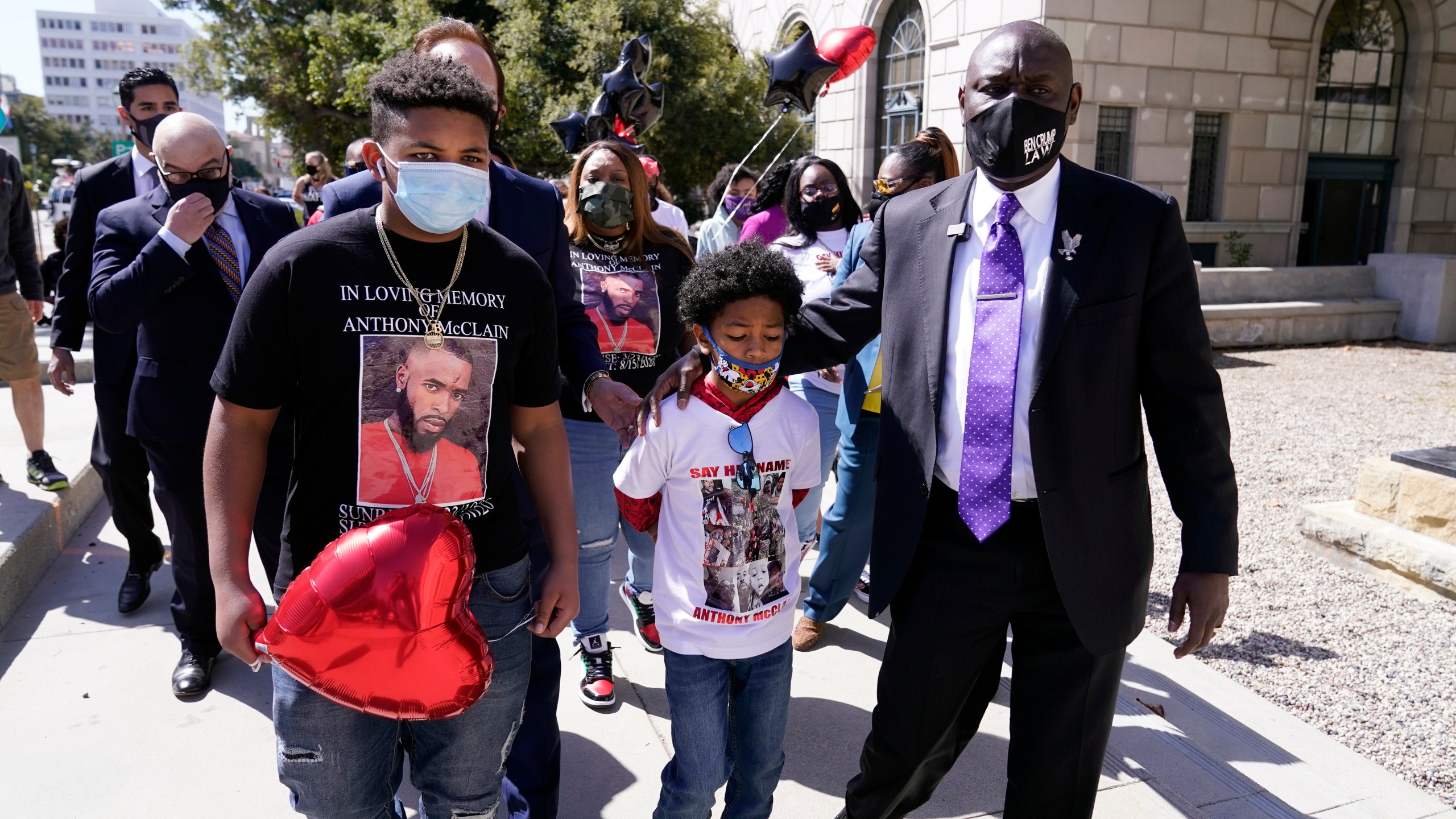 Attorney Ben Crump, right, walks with Anthony McClain's sons Anthony Jr., center, and Bryce, left, during a press conference announcing new developments on the McClain case on March 22, 2021, in Pasadena, Calif. (AP Photo/Marcio Jose Sanchez)