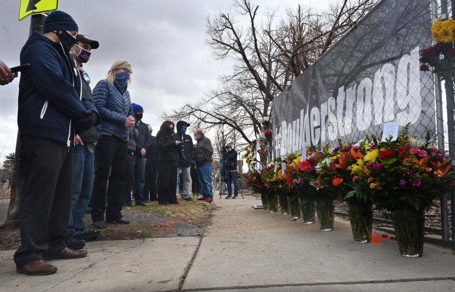 A solemn group of King Soopers employees, left, some from the Boulder store and some from the same district, brought large displays of flowers for each of the victims of a mass shooting at a Boulder Kings Soopers store. (Jerilee Bennett/The Gazette via Associated Press)