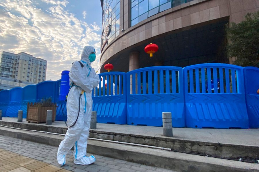 In this file photo dated Saturday, Feb. 6, 2021, a worker in protectively overalls and carrying disinfecting equipment walks outside the Wuhan Central Hospital where Li Wenliang, the whistleblower doctor who sounded the alarm and was reprimanded by local police for it in the early days of Wuhan's pandemic, worked in Wuhan in central China. A lengthy written report published Thursday March 25, 2021, from a team of international and Chinese scientists on a joint mission to Wuhan aims to help unearth the origins of the coronavirus since it was first detected in China more than a year ago. (AP Photo/Ng Han Guan, FILE)